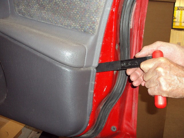 A man using extended clip release tool on a car
